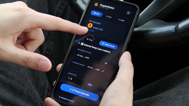 Person uses a mobile crypto wallet to switch between digital assets and prepare an internal transfer, reflecting the rise of self-managed finance and blockchain payments.
