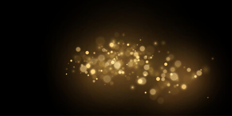 Golden particles glow with warm light on black. Soft sparkles create an elegant mood. Abstract holiday background. © Extrastock