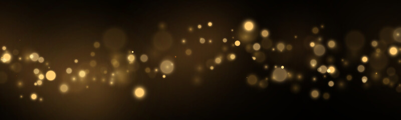 Soft gold lights sparkle through a dark background. Floating glitter creates an airy effect. Magical holiday design. © Extrastock