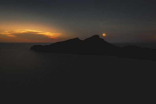 Sant Elm, Balearic Islands, Spain - 12 August 2026: Aerial view of the total solar eclipse over the island of Sa Dragonera at sunset, with the dark silhouette of the island against a glowing horizon.