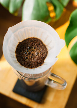Pour over filter with ground coffee in the funnel in focus. Drip filter coffee brewing. Pour over alternative method of pouring water over roasted and ground coffee beans contained in filter