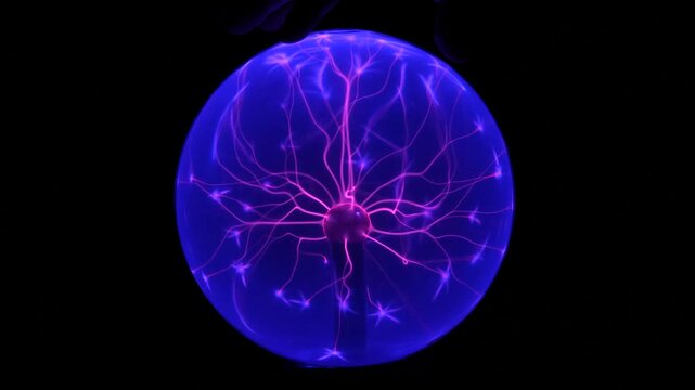 Boule plasma interactive avec une main touchant la surface, g&eacute;n&eacute;rant des filaments lumineux color&eacute;s. Exp&eacute;rience scientifique et effet &eacute;lectromagn&eacute;tique fascinant sur fond sombre.