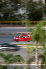 Fototapeta premium Red Fiat Siena side profile moving with roof rack ladder, Compact sedan driving on road