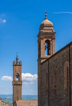 die Kirche Oro di Montalciono Complesso di Santi mit dem Turm des Palazzo dei Priori im Bildhintergrund, Montalcino, Toskana, Italien