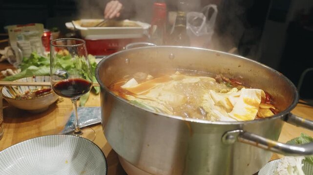 Slow-motion close-up of bubbling spicy hot pot with red wine and side
