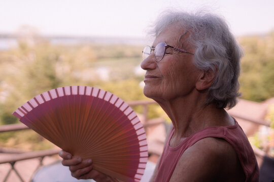 elderly woman cooling down with a fan during a heatwave