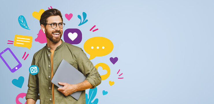 Smiling Young Caucasian Male Working On Laptop At Creative Office Environment, Surrounded By Colorful Graphics, Displaying Happiness And Engagement, Concept Of Business And Creativity.