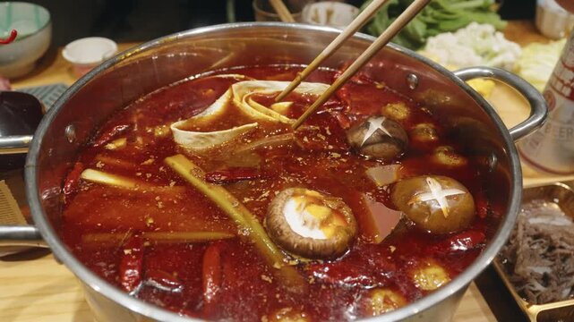 Placing Duck Blood into Spicy Red Oil Hot Pot with Chopsticks