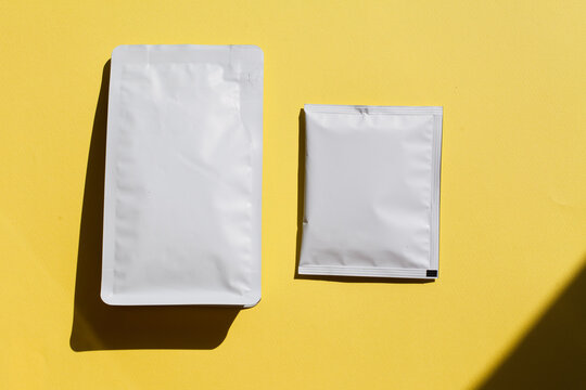 Blank craft plastic pouch, white pack on studio background with shadow, mylar bag isolated for coffee or food, cosmetic products, snack, candy. Different sizes, mock up.