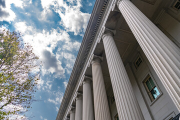 Fototapeta premium Low angle Treasury colonnade creates strong perspective against a bright cloudy sky.