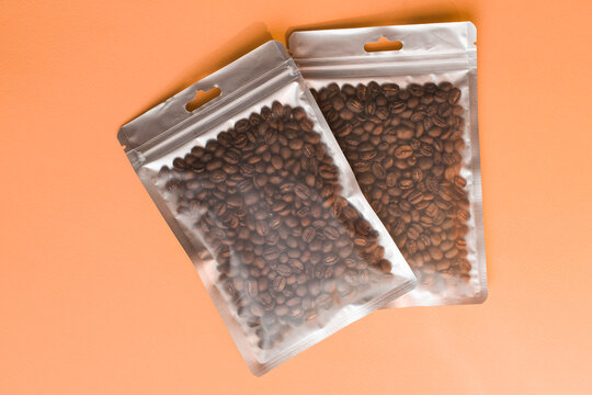 Blank craft plastic pouch mock up with coffee beans inside, transparent pack on studio background with shadow, mylar bag isolated for coffee product