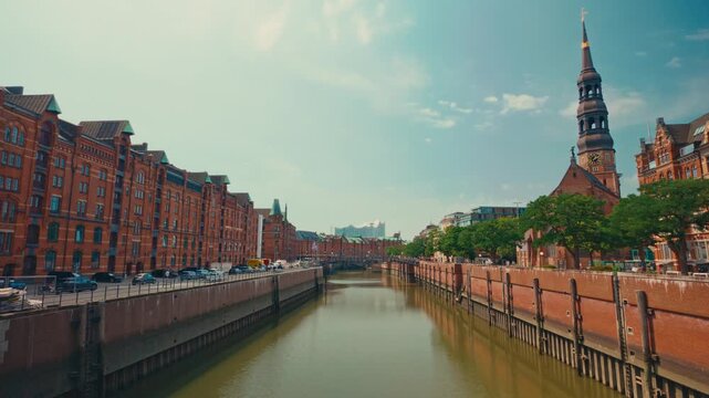 Hamburg Speicherstadt canal with red brick warehouses, St. Catherine's Church, Elbphilharmonie in historic HafenCity under clear sunny summer sky in Germany