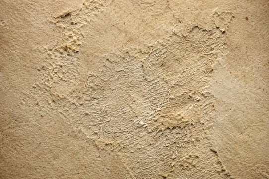 Rough textured cardboard surface displays a distressed and uneven beige tone corrugated fiberboard texture tan brown paper material roughness worn damaged grainy close up macro background