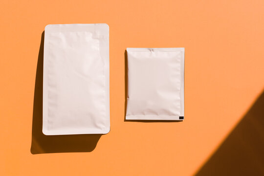 Blank craft plastic pouch, white pack on studio background with shadow, mylar bag isolated for coffee or food, cosmetic products, snack, candy. Different sizes, mock up.
