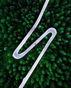 Aerial View of a Dramatic Hairpin Road Winding Through a Dense Green Forest