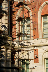Fototapeta premium Scaffolding is positioned against a historic brick building featuring large windows and intricate architectural details in Tsaritsyno Park, Moscow
