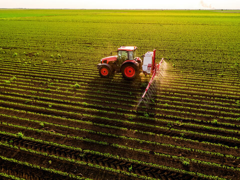 Tractor spraying soybean field with herbicide by drone