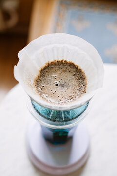 Pour over filter with ground coffee in the funnel in focus. Drip filter coffee brewing. Pour over alternative method of pouring water over roasted and ground coffee beans contained in filter