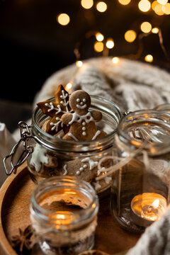 Aromatic christmas handmade candle with the sweet scent of gingerbread cookies. Cozy holiday home atmosphere, aromatherapy. Interior composition with burning candles, anise, cinnamon, pine cones