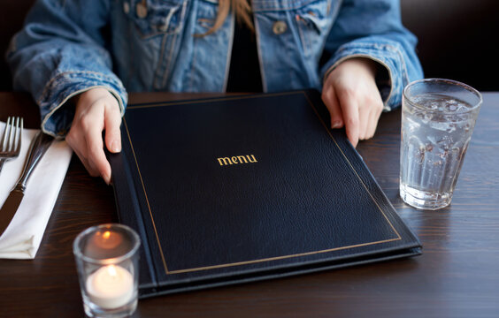 Couple enjoys selecting dishes from an elegant menu while dining at a cozy restaurant with a glass of water on the table