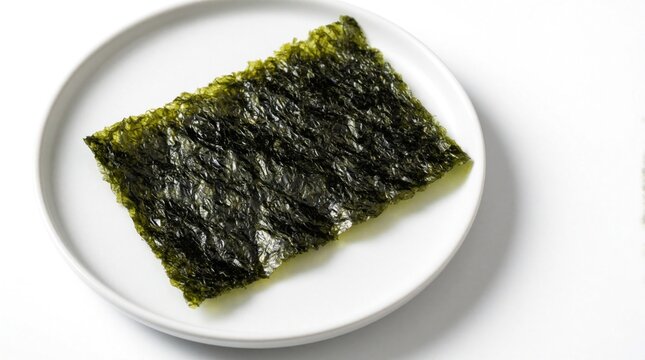 Crispy dried seaweed sheet rests on simple white plate. This healthy, savory snack is popular in Asian cuisine, often seasoned and enjoyed alone or with rice. Provides essential nutrients.