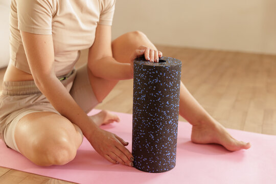 Woman Preparing Calf Massage With Foam Roller On Yoga Mat