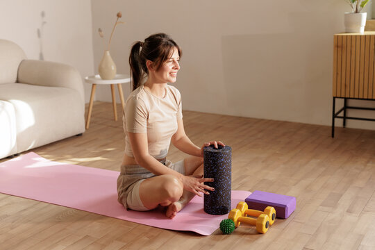 Woman Using Massage Roller For Self Massage On Yoga Mat