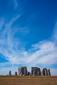 The prehistoric megalithic structure Stonehenge during a summer afternoon with dry, brown grass in the foreground