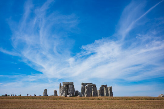 The prehistoric megalithic structure Stonehenge during a summer afternoon with dry, brown grass in the foreground