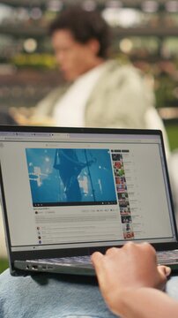 Vertical screen: The African American student listens to an online concert video during a campus study break, with a broadcast music performance playing on the laptop.