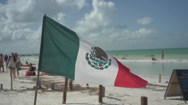 Slow motion of Mexican flag waving in the wind on a beach in Holbox, Mexico
