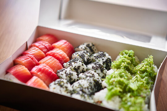  Assorted sushi rolls arranged on in a box, featuring maki rolls with salmon, tuna, tamago surimi, avocado, lettuce, cucumber and other vegetable fillings. 