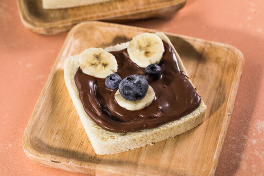 breakfast serving funny face animal dog on the plate (toast, chocolate spread and banana, berry)
