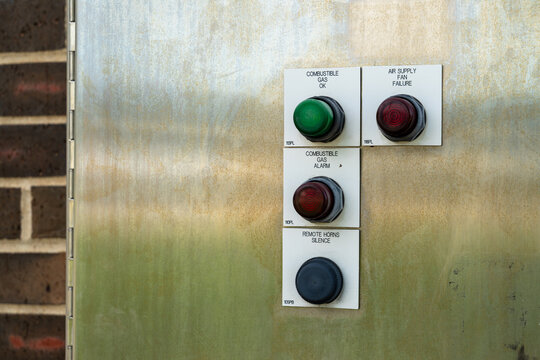 Close up of an industrial control panel with indicator lights and a pushbutton on a stainless steel enclosure
