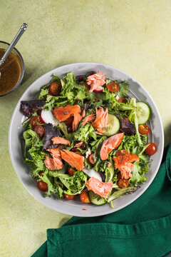 Salmon fish salad. Fresh vegetable greek salad with tomato,lettuce, cucumbers, fand grilled salmon fish fillet in bowl, healthy food, omega 3, keto diet, mediterranean cusine, top view.