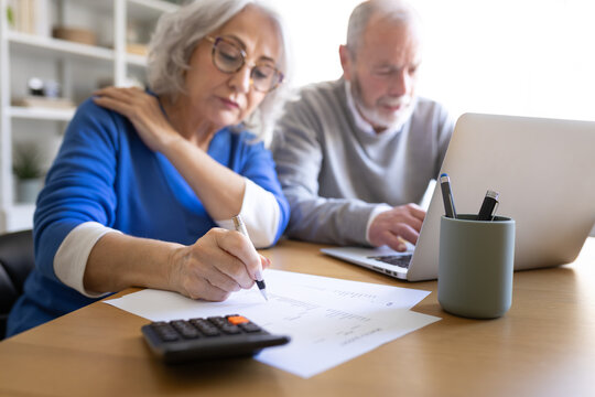 Senior couple managing domestic finances and calculating bills at home