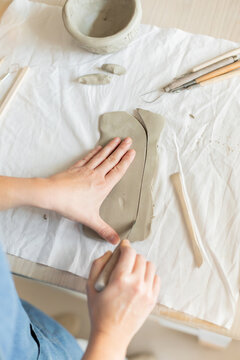 Women artist pottery shaping clay on a worktable with tools and cloth
