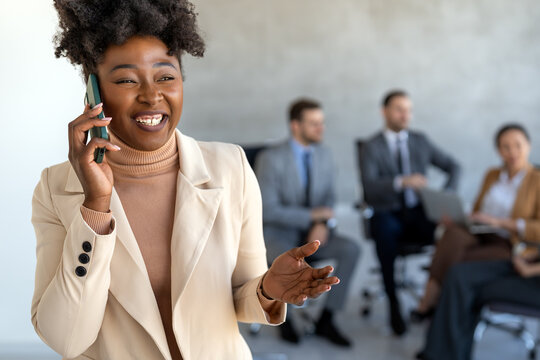 A confident businesswoman leads her busy office life, multitasking with smartphone communication