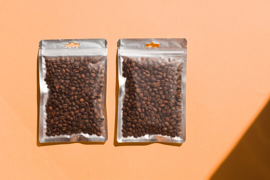 Blank craft plastic pouch mock up with coffee beans inside, transparent pack on studio background with shadow, mylar bag isolated for coffee product