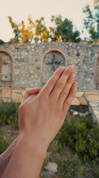 A woman hands joined in prayer to end wars in the world near crucifix religious