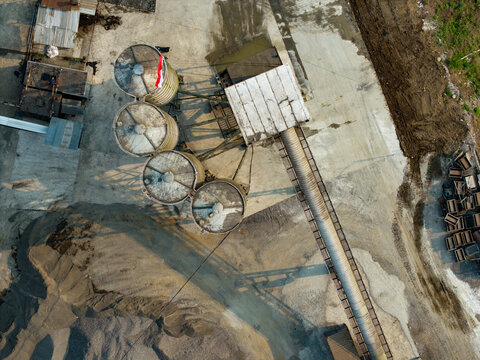 Aerial view of industrial silos and a long conveyor belt at a processing facility in Indonesia.