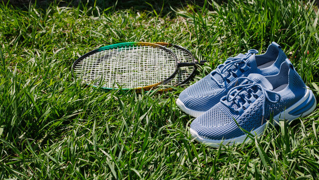 composition with racket and tennis shoes on green grass background. Concept of active recreation, sports, and weight loss. flat lay, top view