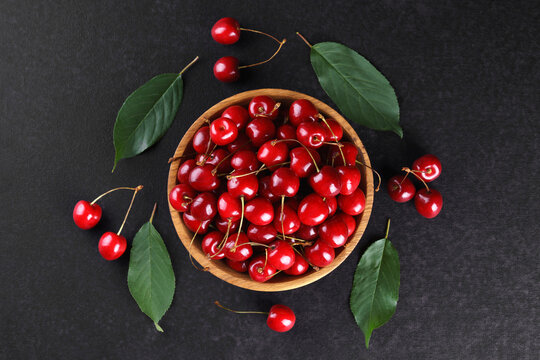 Fresh ripe sweet cherries in rustic wooden bowl on black stone textured background with copy space for text. Juicy organic summer fruit, red berries, healthy seasonal food, farm harvest