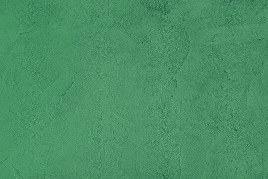 Green stucco wall, uneven plaster surface, painted distressed concrete texture background. Abstract grunge backdrop, wallpaper for design, construction design element