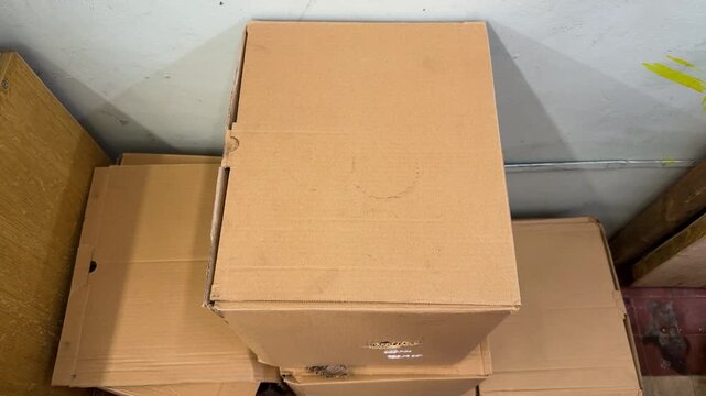 Brown cardboard boxes stacked in corner near white wall for storage or moving. Relocation day, packing things, warehouse clutter, old packaging