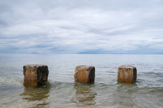 World War II concrete anti tank blocks standing in the water off the coastline of Lossiemouth in the Moray region of Scotland on a cloudy day