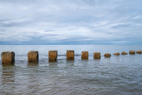 World War II concrete anti tank blocks standing in the water off the coastline of Lossiemouth in the Moray region of Scotland on a cloudy day