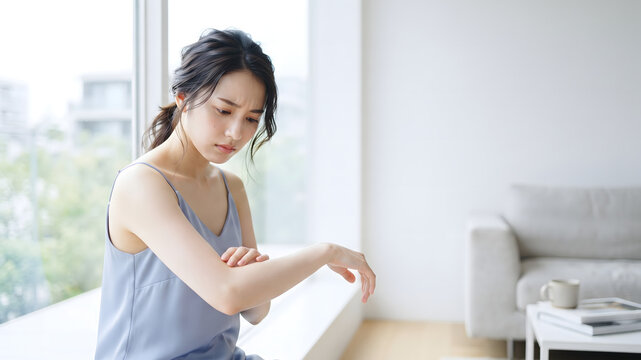 Woman rubbing irritated dry skin on her forearm at home
