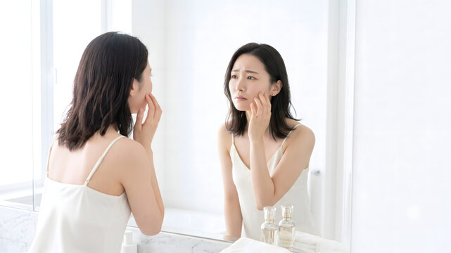 Concerned woman examining facial skin closely in a mirror