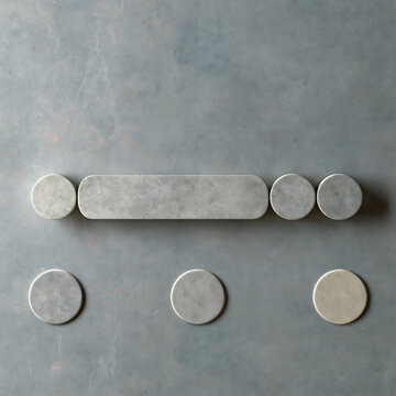 A collection of smooth gray stone circles and one elongated rounded rectangle arranged on a textured gray surface with soft natural lighting
